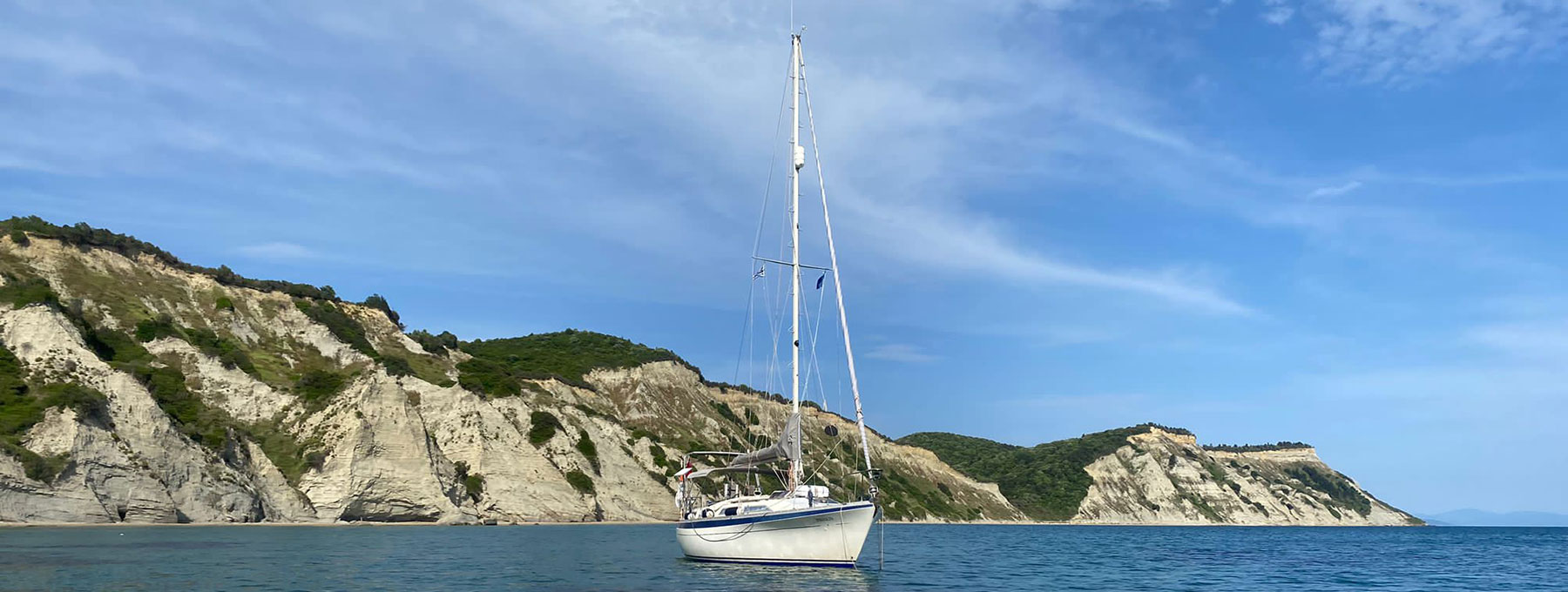 Sailing yacht anchored with Greek island in the background